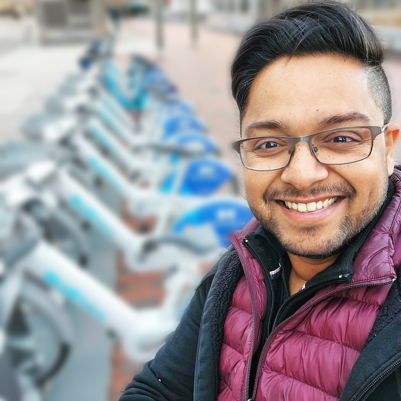 Joel smiling in front of a full rack of bikeshare bikes